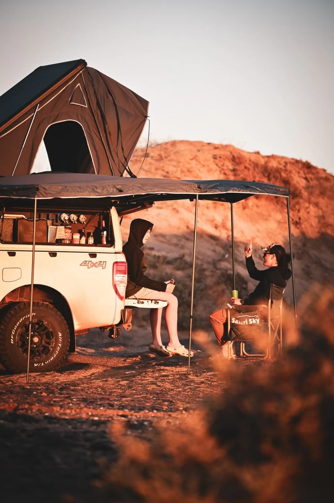Bakkie with rooftop tent at sunset on red dirt road in the Karoo
